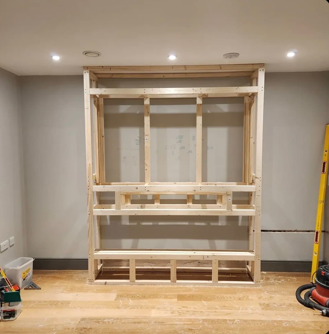 Framed media wall under construction with wiring chases marked out
